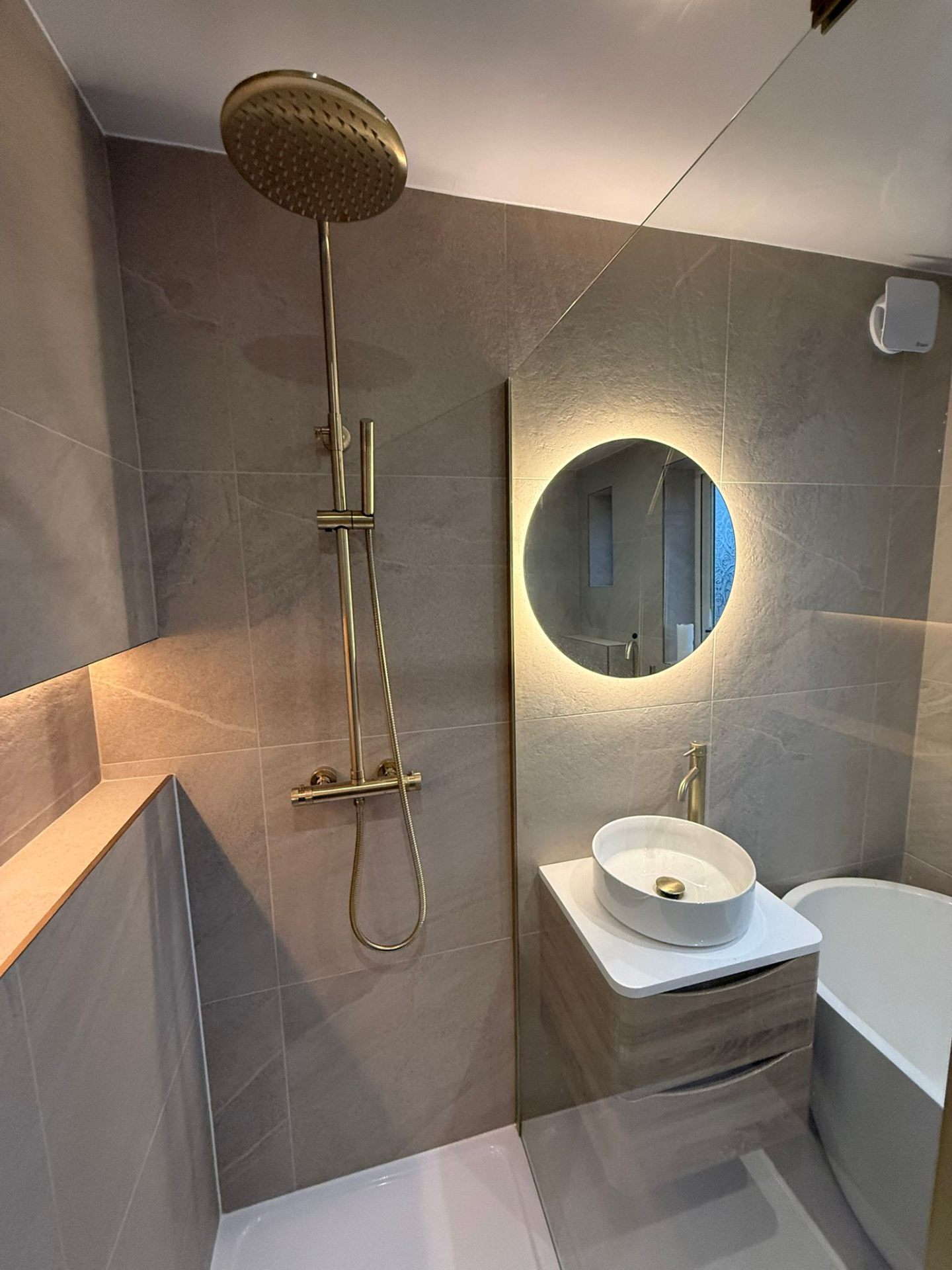 Modern walk-in shower with gold rainfall head, LED niche lighting, and vessel sink vanity in Chorlton