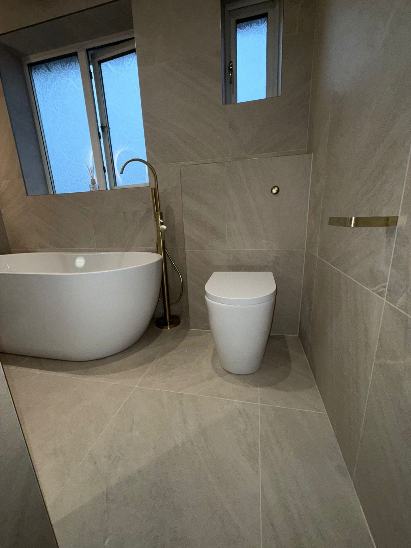 Freestanding bath and wall-hung toilet installation with gold fixtures in Eccles, Salford
