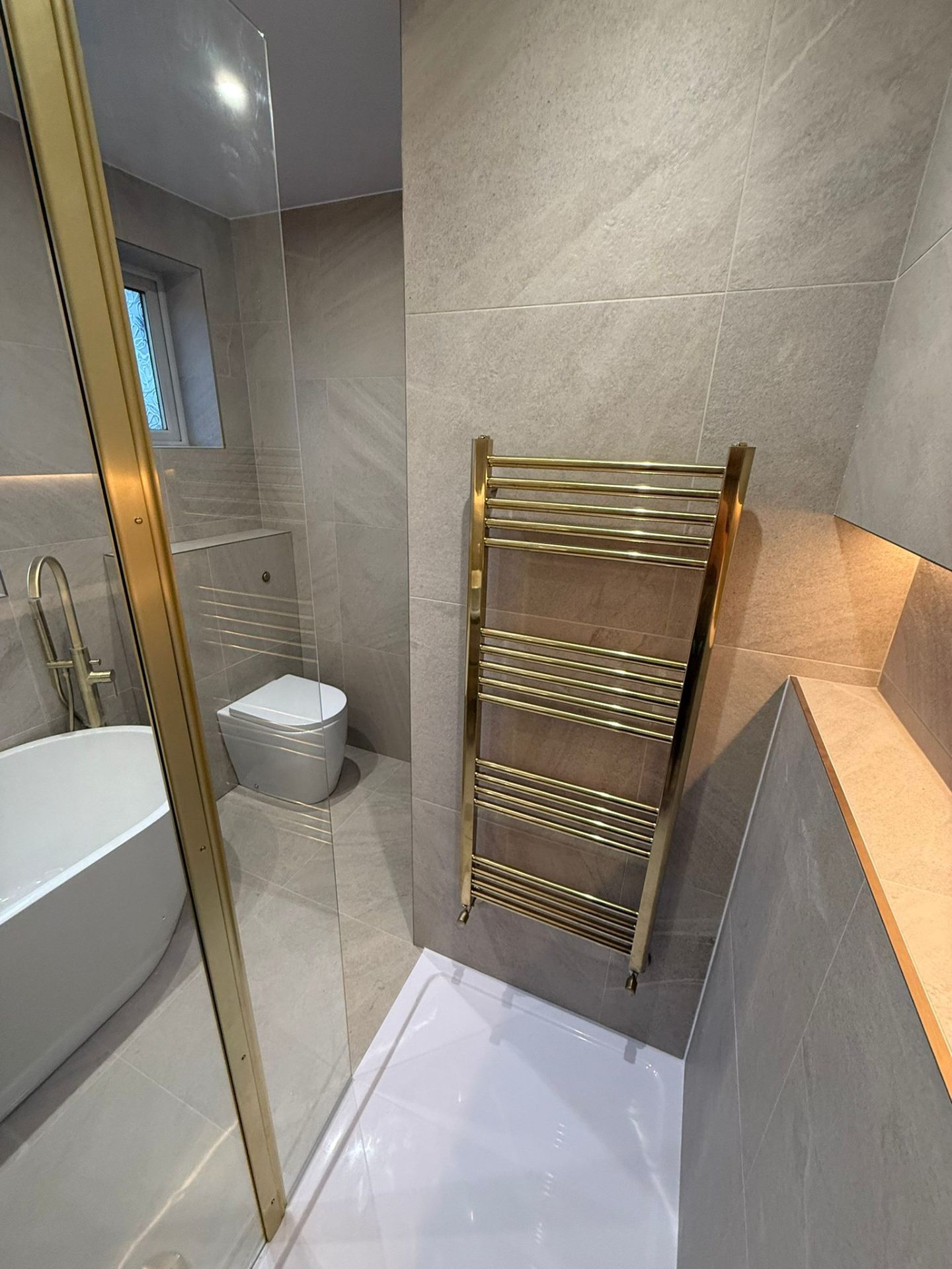 Bathroom renovation featuring gold heated towel rail and freestanding bath in Heaton Moor